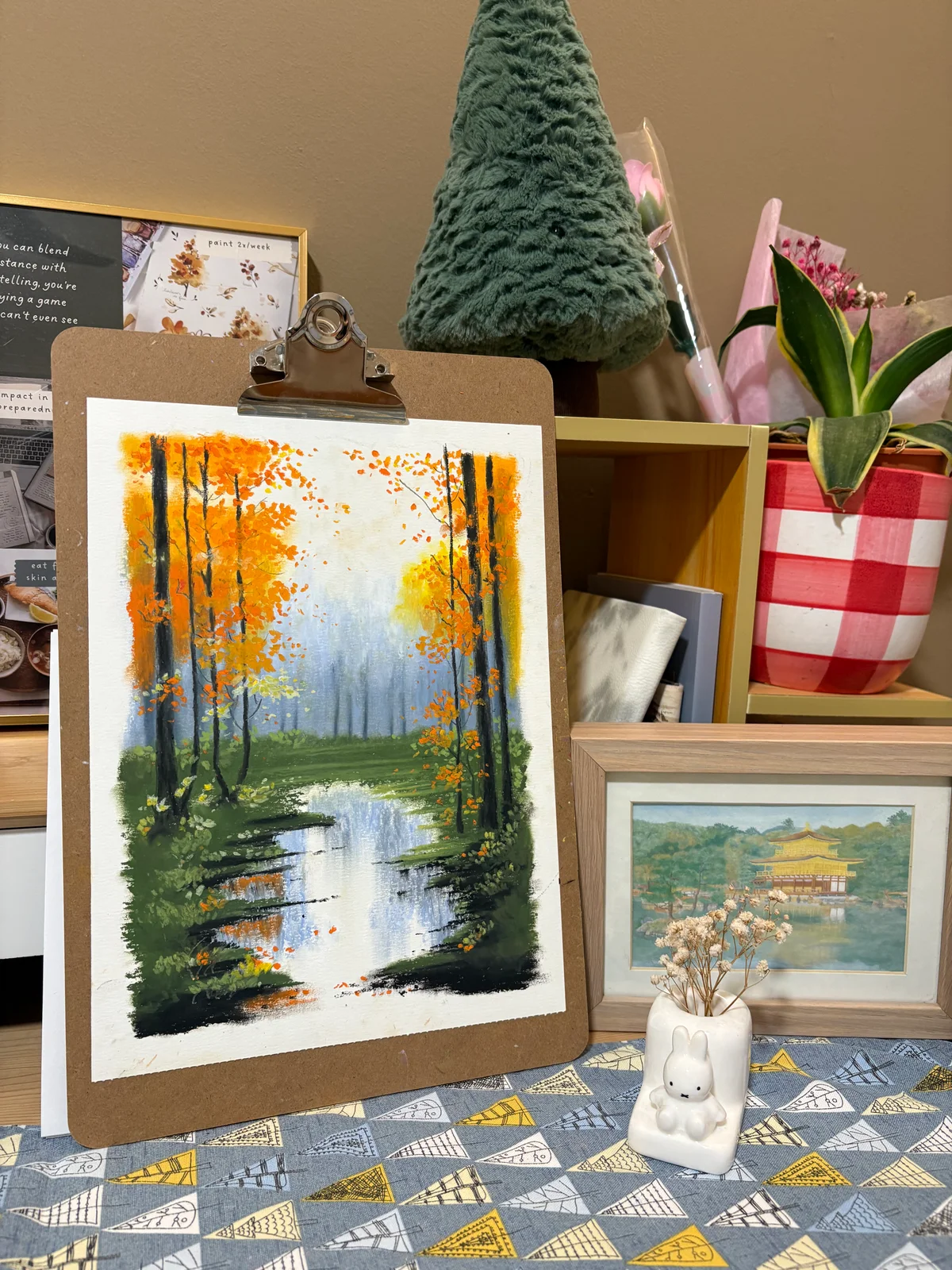 Painting of a stream running between tall trees with orange autumn leaves.